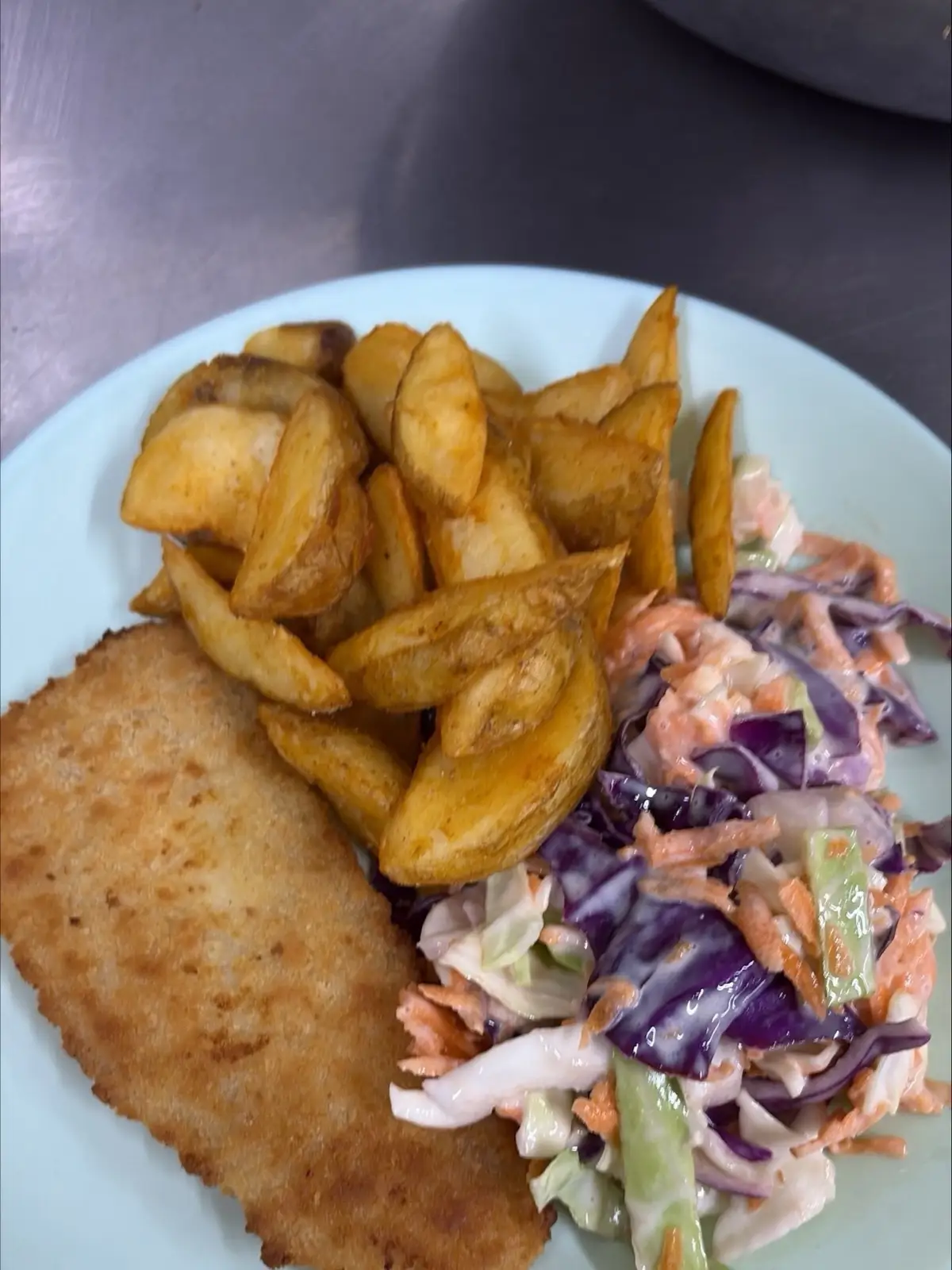 Crumbed fish with potato wedges and coleslaw, plated in the Christine Court kitchen