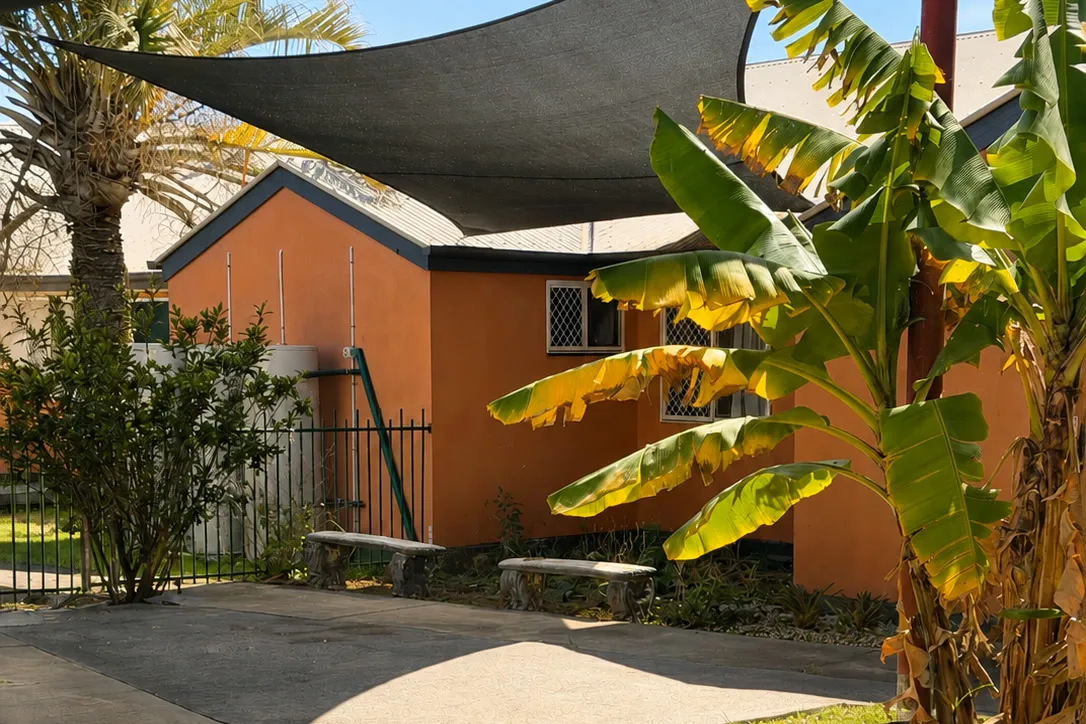 Garden with shade sails and bench seating at Christine Court