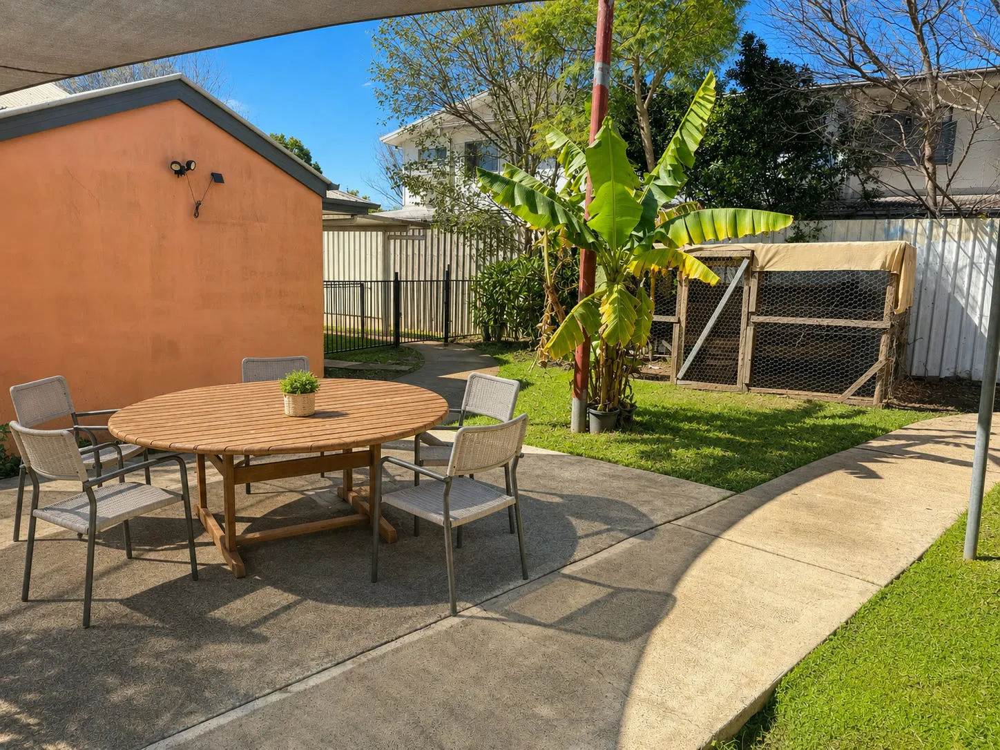 Outdoor dining table and chairs under shade sails at Christine Court