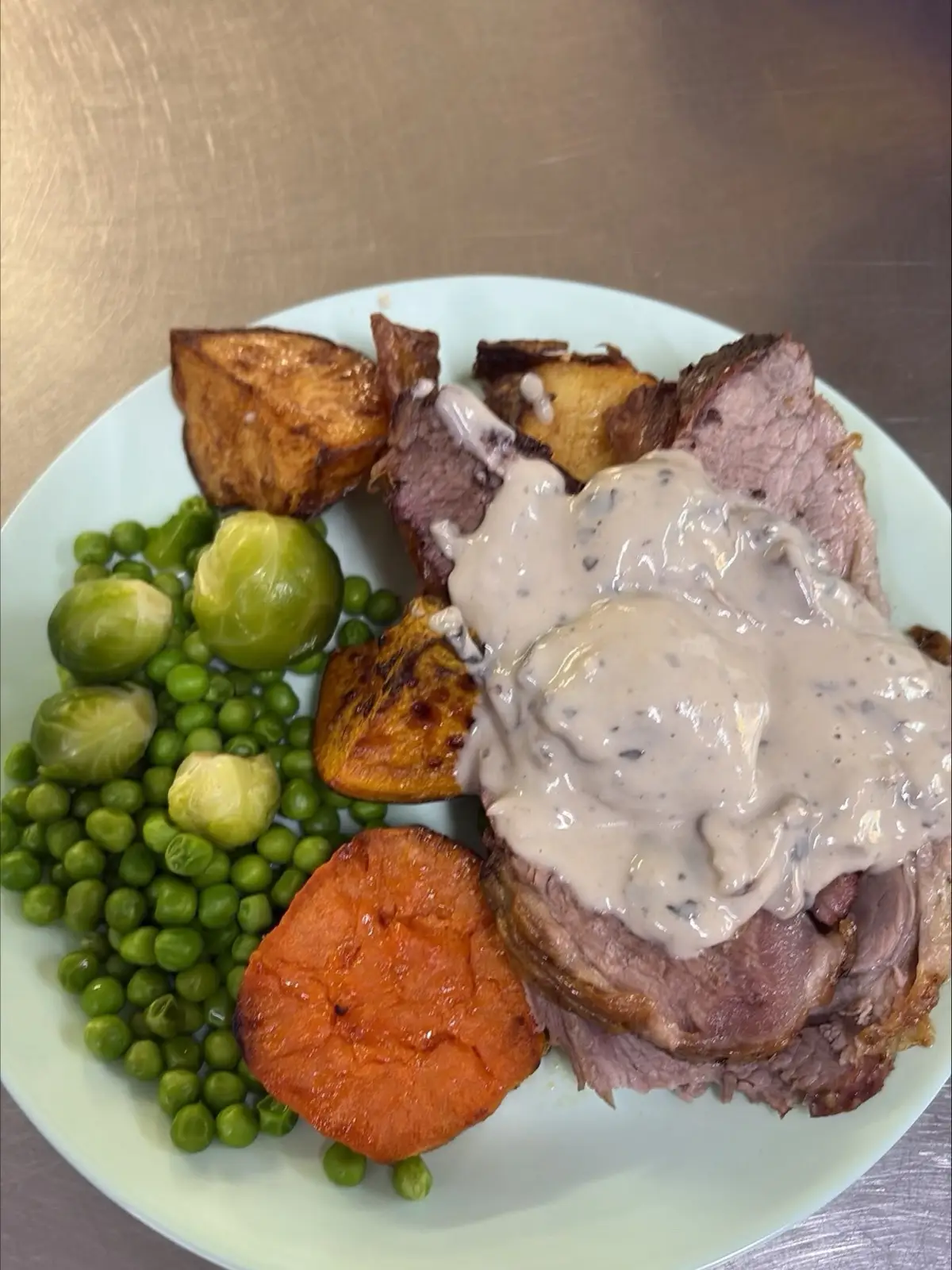 Roast beef with mushroom gravy, roast potato, pumpkin, sweet potato, peas and Brussels sprouts, plated in the Christine Court kitchen